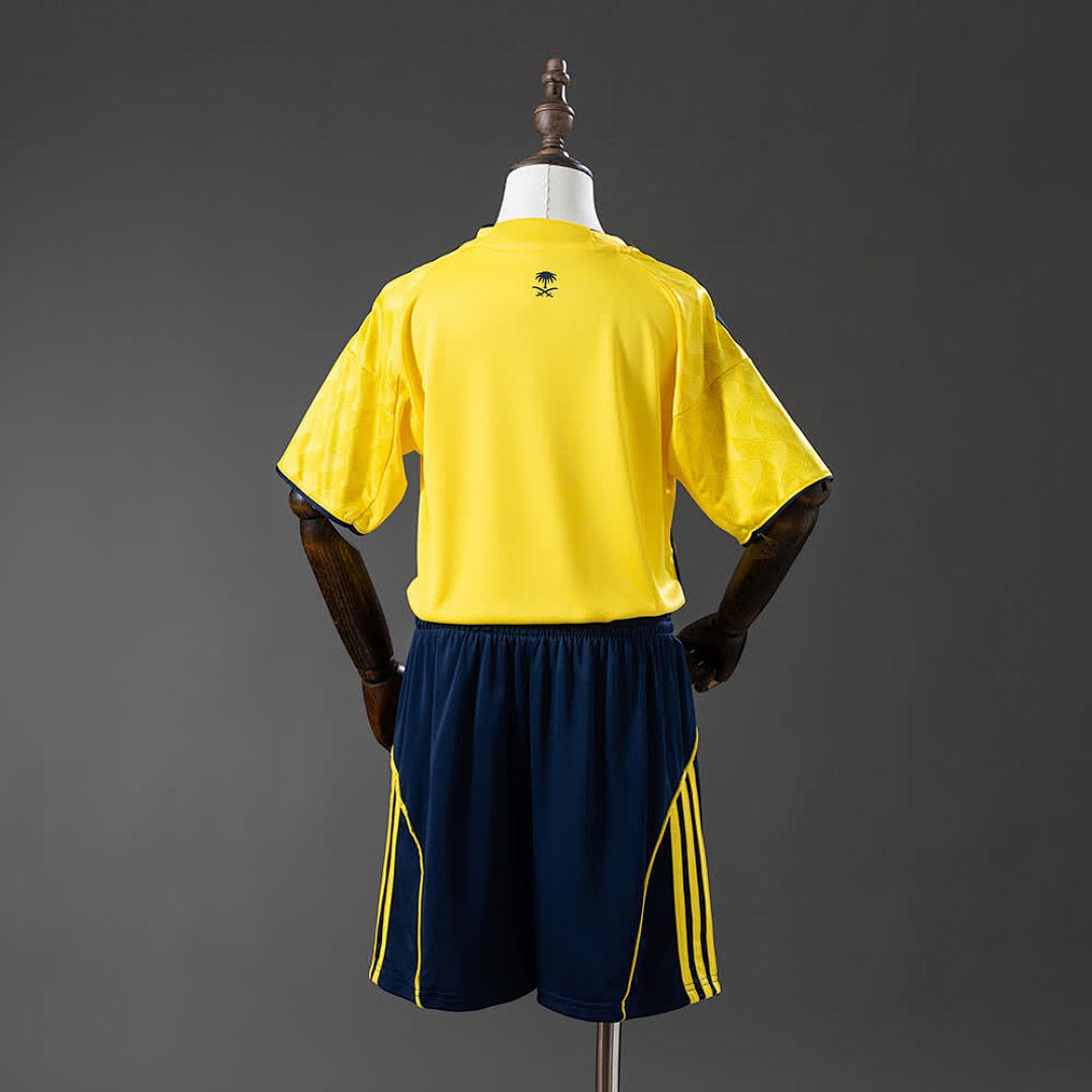 Al Nassr Kids Home 25/26 — back view of yellow shirt with Saudi crest and navy shorts